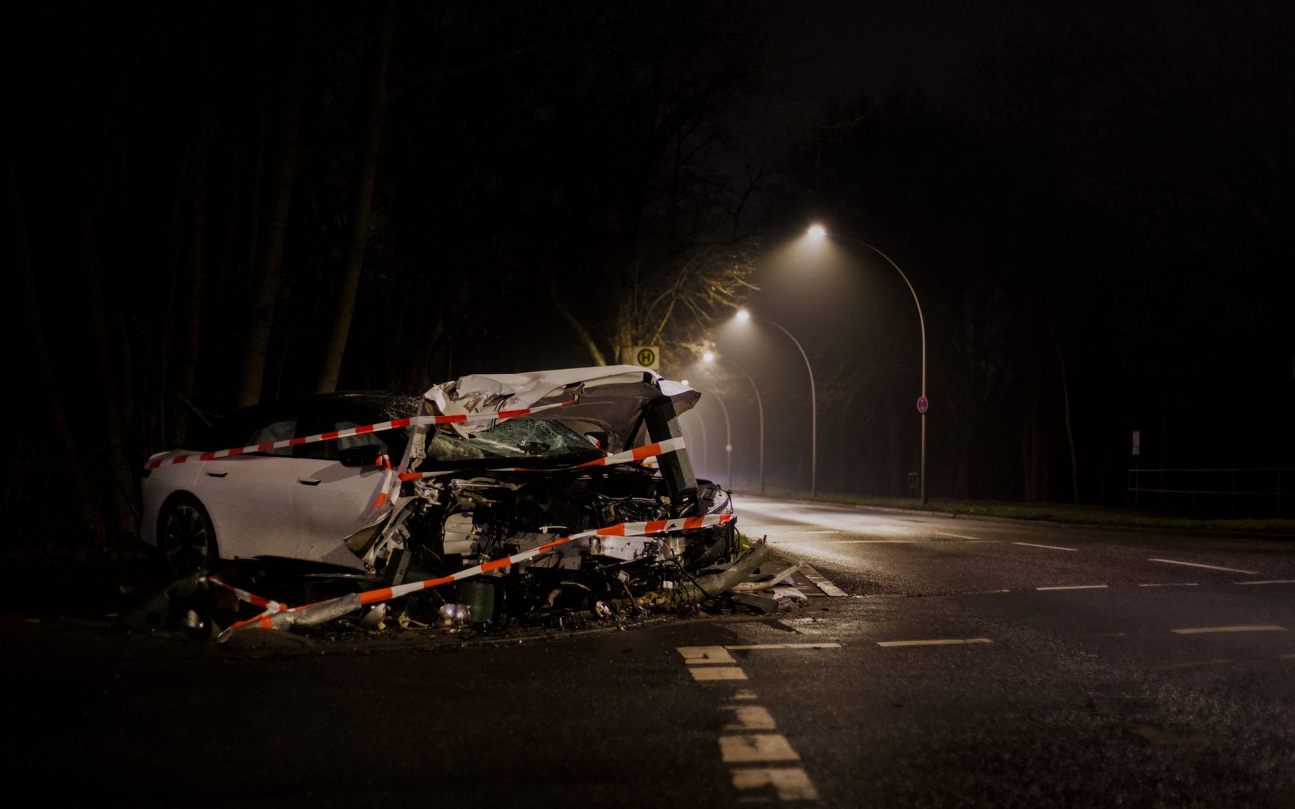 A wrecked car after a crash on a dimly lit street in Berlin at night.